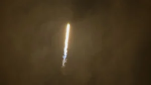Rocket ascending through thick Venusian-style atmosphere, trailing fire and vapor.