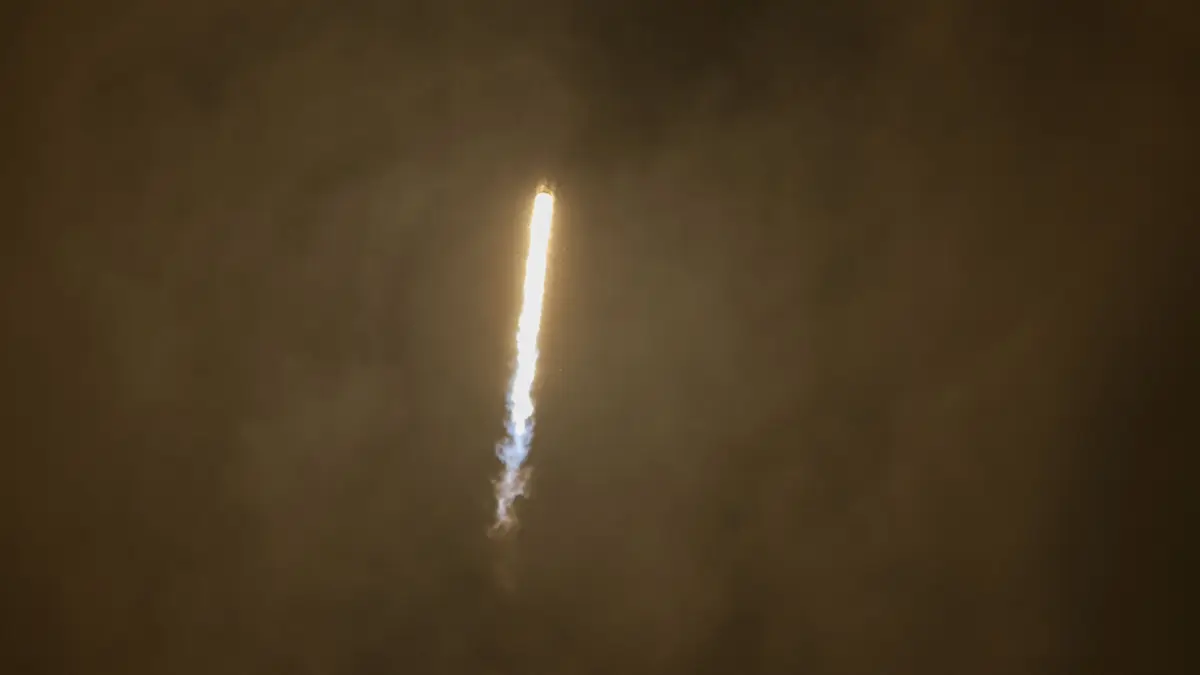 Rocket ascending through thick Venusian-style atmosphere, trailing fire and vapor.