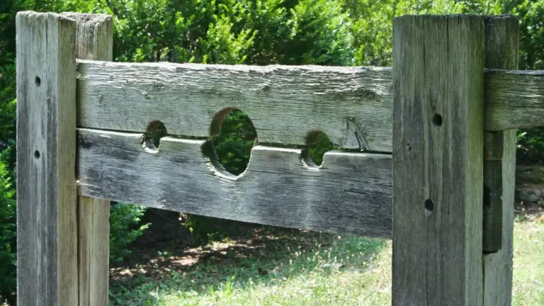 Weathered wooden stocks used for public punishment, symbolizing social shaming and intolerance of dissent.