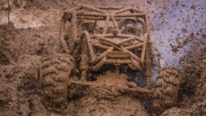 Mud-covered off-road vehicle struggling through deep, waterlogged terrain