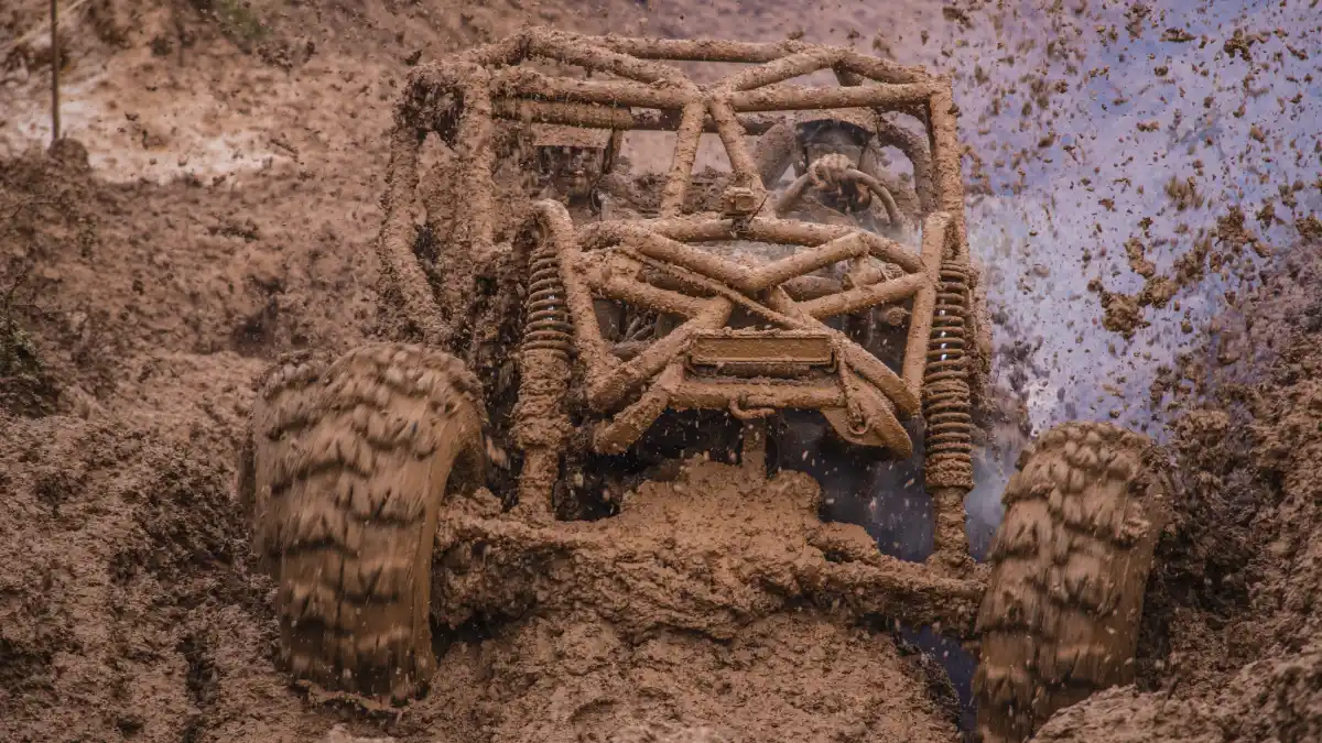 Mud-covered off-road vehicle struggling through deep, waterlogged terrain