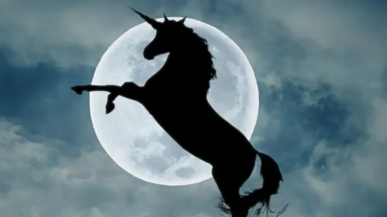 A silhouetted unicorn rearing in front of a full moon against a cloudy night sky.