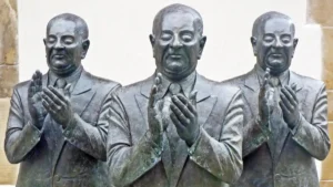 Bronze statues of identical men in suits clapping, symbolizing conformity and empty applause.