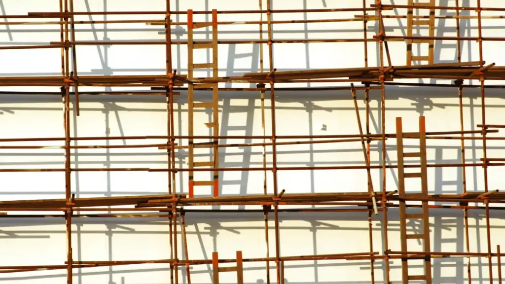 Wooden ladders and scaffolding form a dense grid across the façade of a building, creating a visual maze of interconnected ladders and platforms.