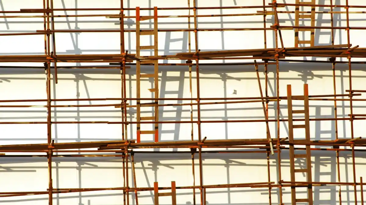 Wooden ladders and scaffolding form a dense grid across the façade of a building, creating a visual maze of interconnected ladders and platforms.
